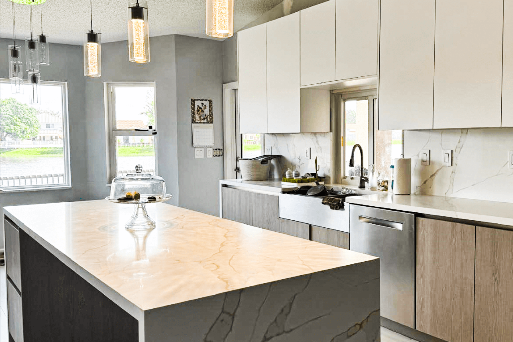 Modern kitchen with white cabinets, marble backsplash, and beige quartz island countertop