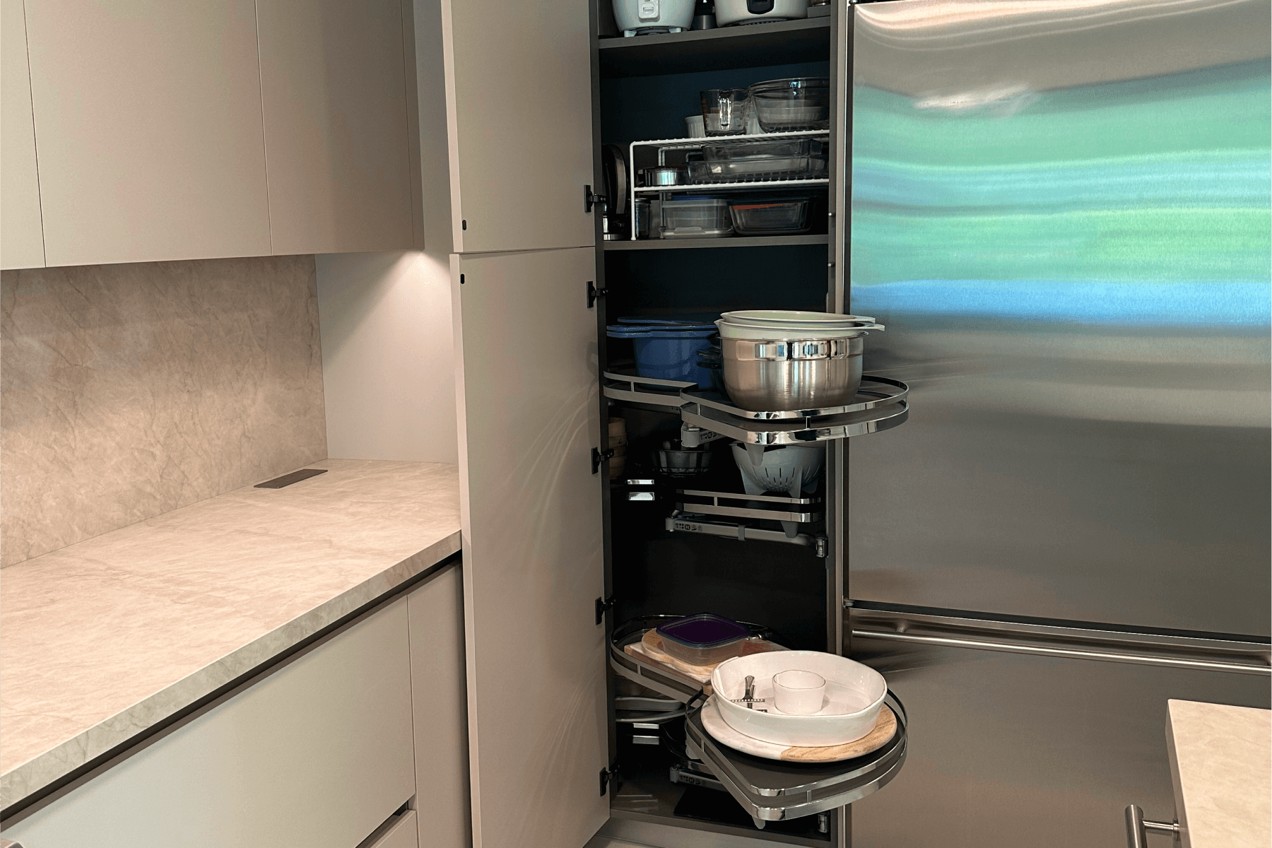 Kitchen cabinet with pull-out rotating shelves organized with pots, pans, and utensils