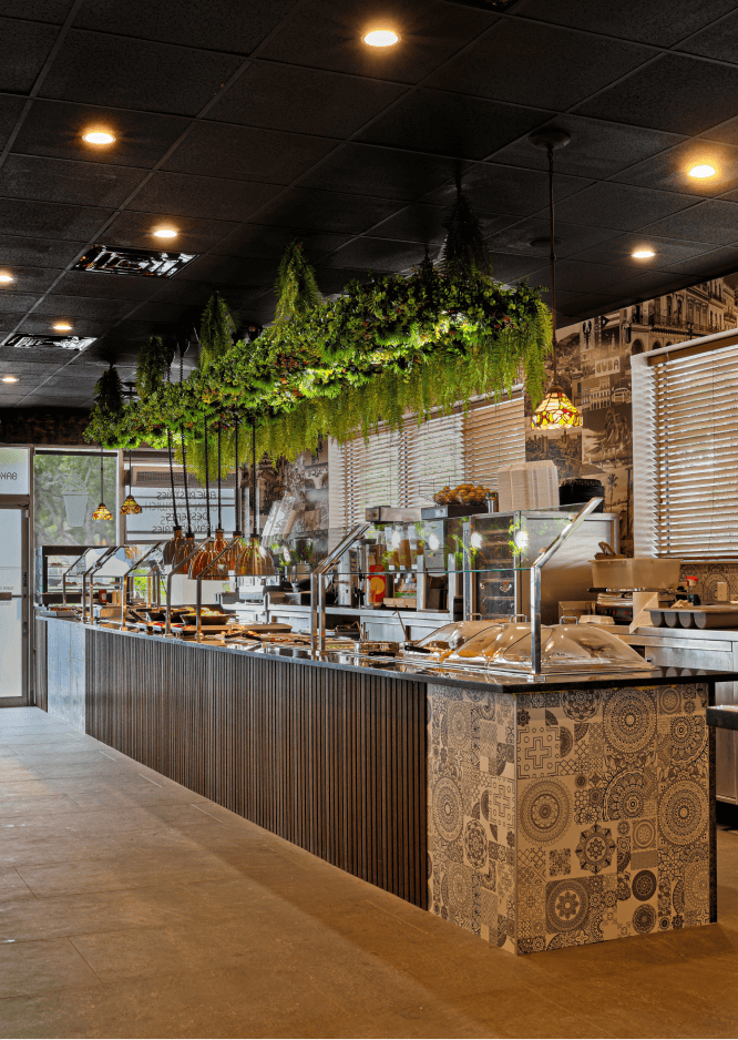 Modern buffet restaurant with greenery decor and food display counter