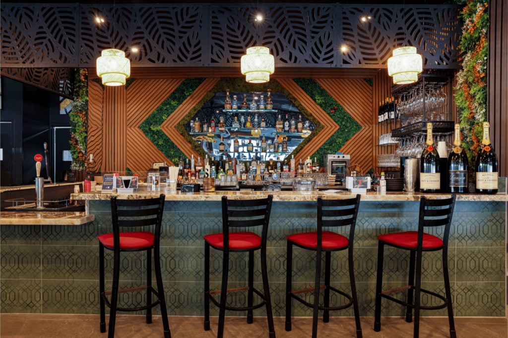 Elegant bar with green wall accents, wooden design, and liquor display at El Sartén