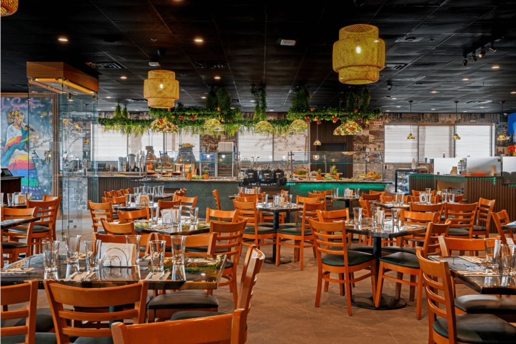 Spacious restaurant interior with wooden tables, greenery decor, and buffet display