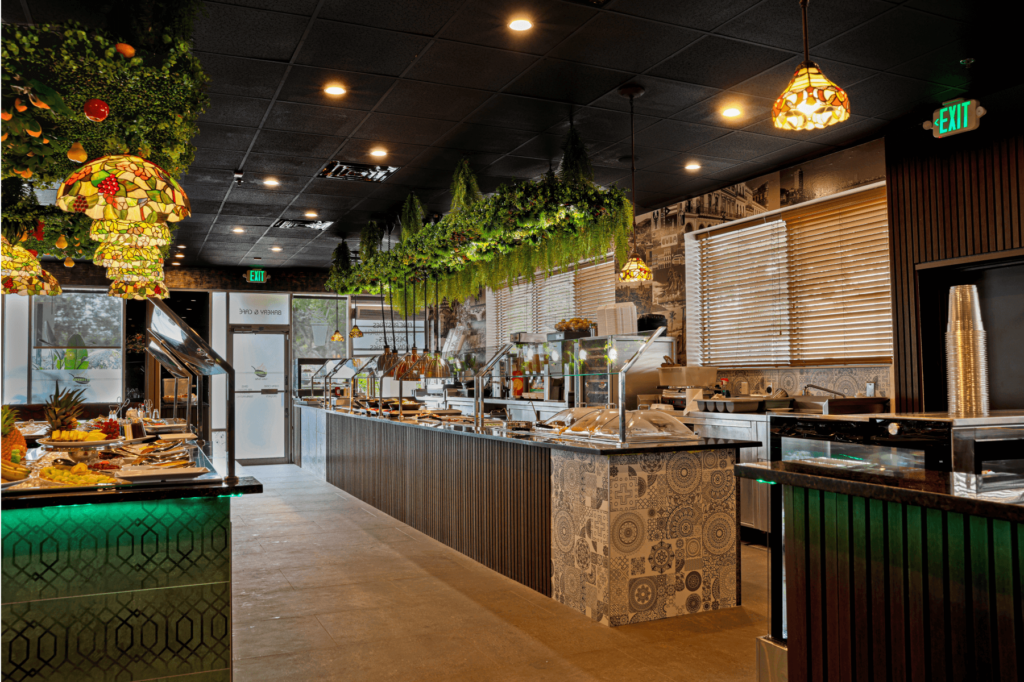 Buffet area in a modern restaurant with greenery decor and stained glass pendant lights