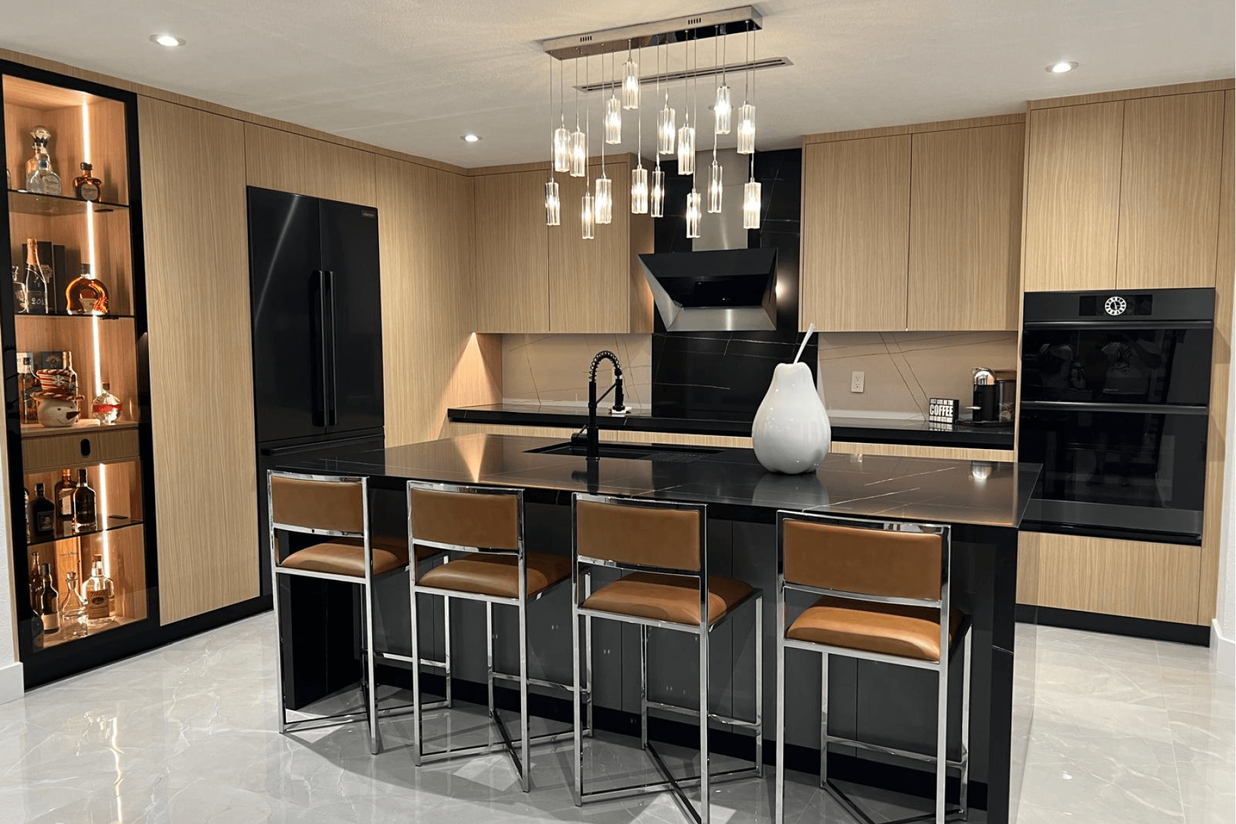 Modern kitchen with black island, wooden cabinets, pendant lights, and built-in liquor display