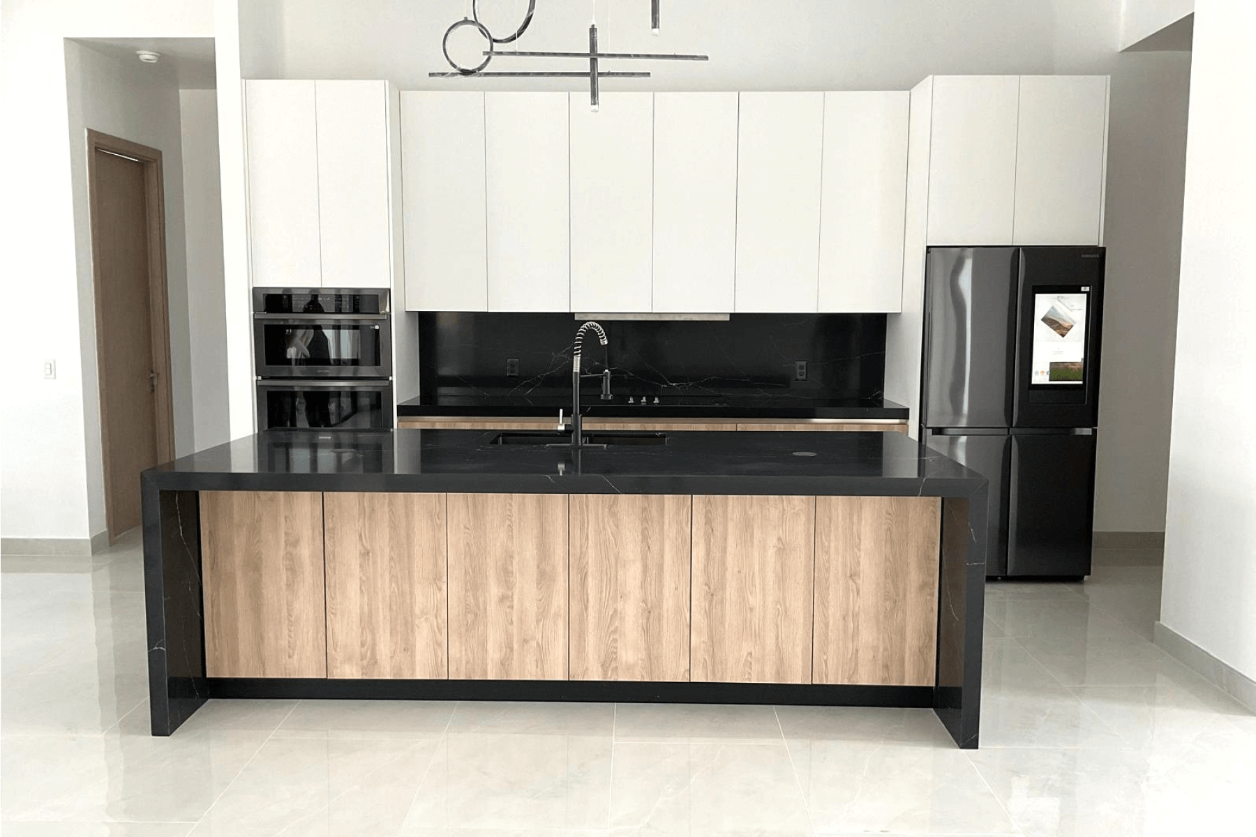 Modern kitchen with black island, wood paneling, white cabinets, and smart refrigerator