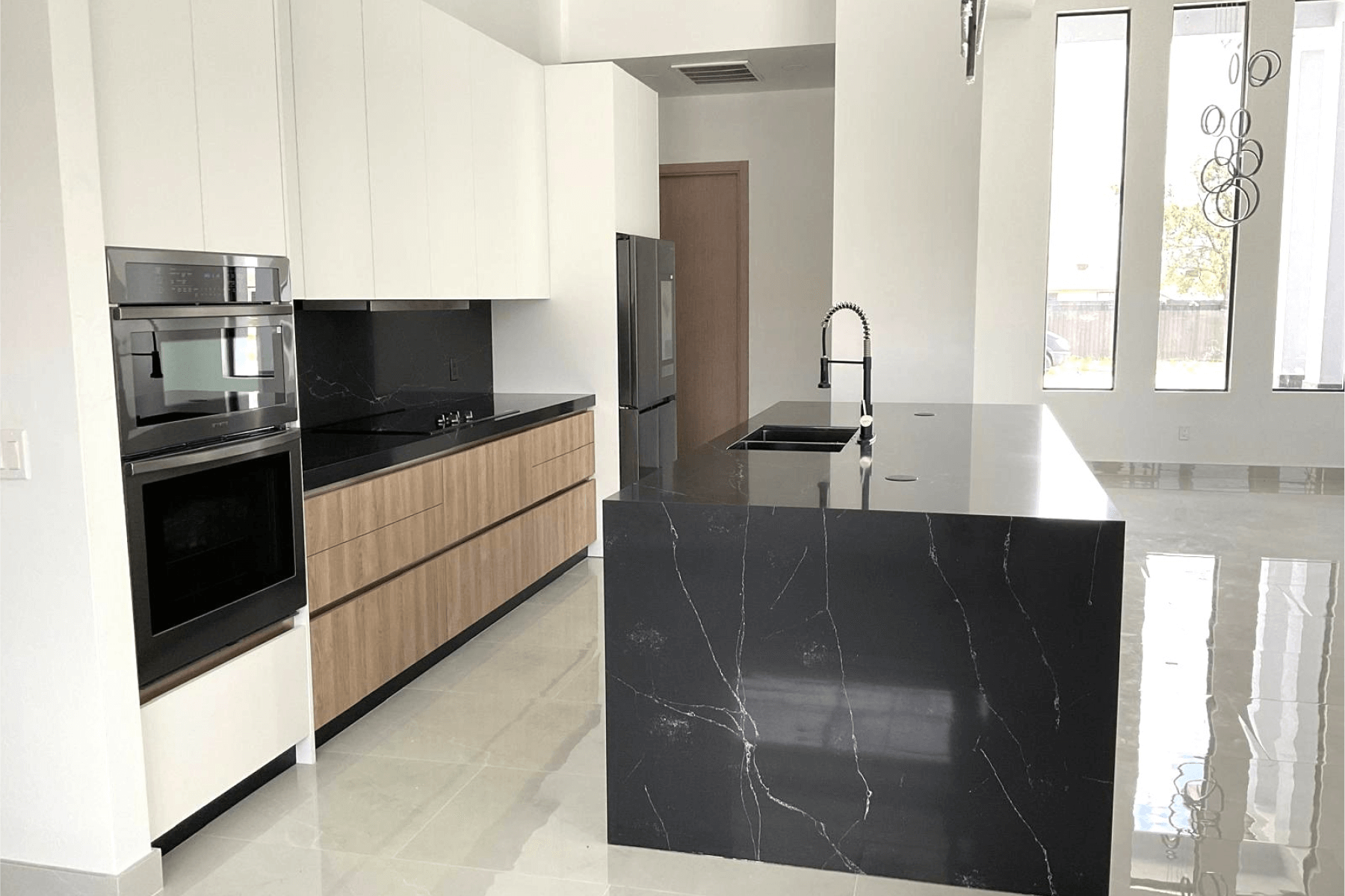 Minimalist kitchen with black marble island, wooden cabinets, and built-in appliances