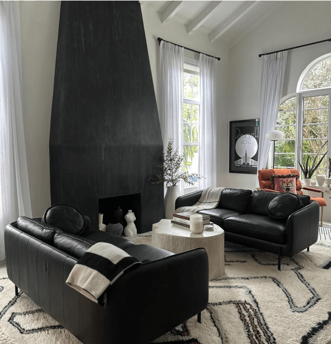 Modern living room with black sofas, high ceiling, and statement fireplace